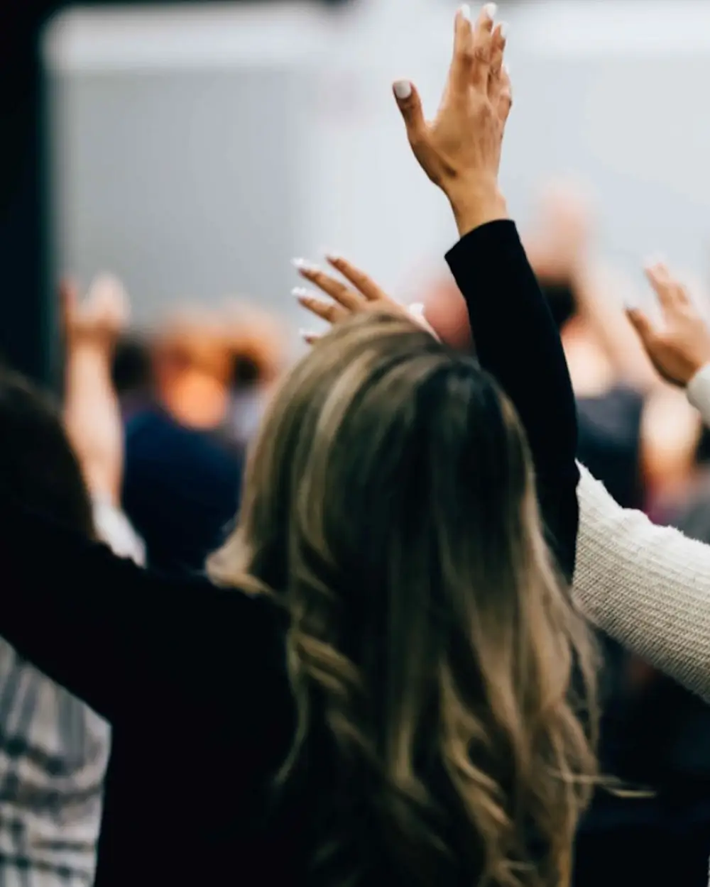 Faith-based marketing consultant in worship with hands raised during church service