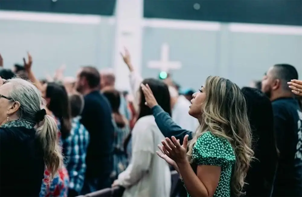 Faith-based marketing consultant Sarry San worshiping during church service surrounded by diverse congregation